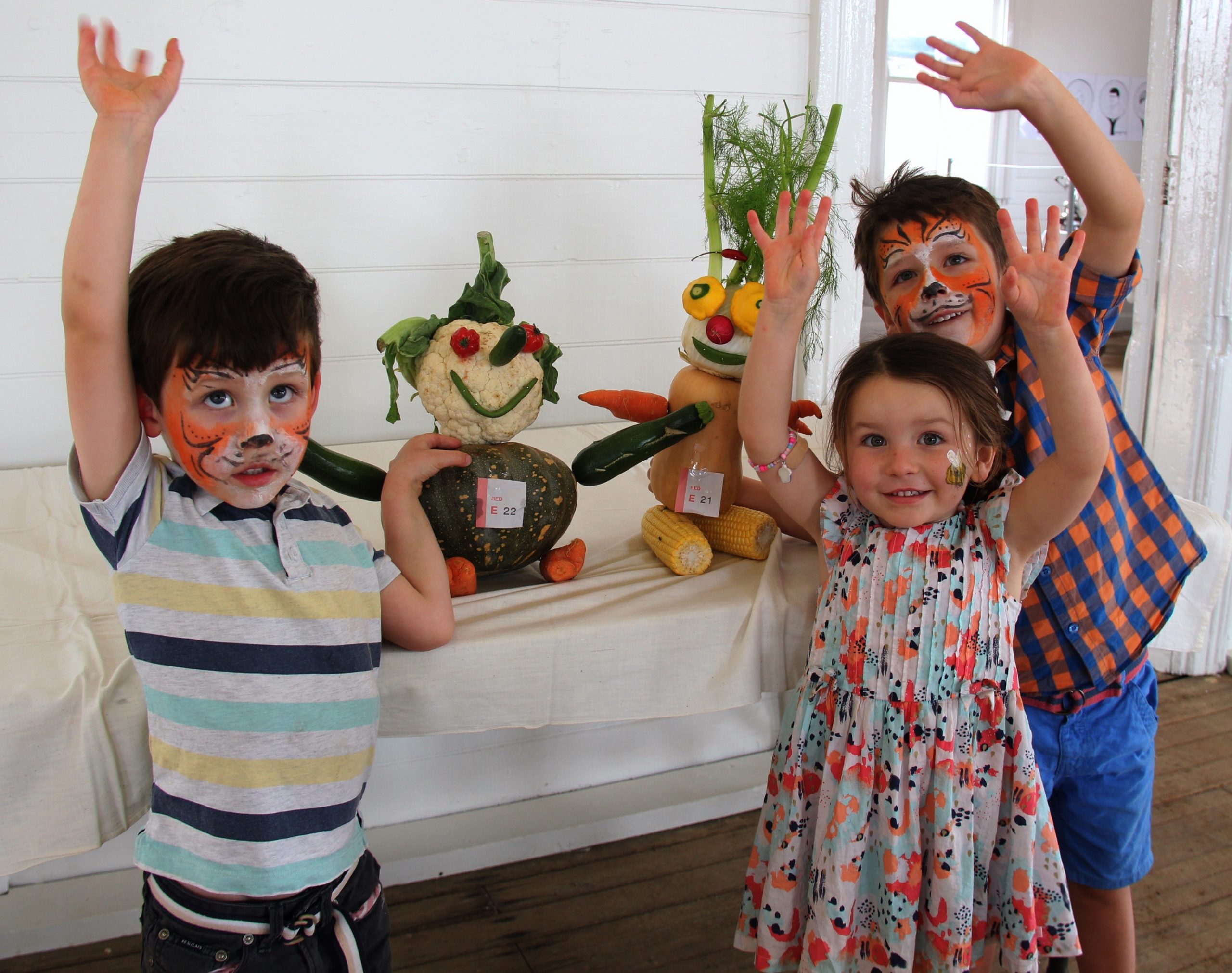Isaac Burton with Hilda and Darcy Hartog displaying the vegetable art created by their clever cousins Matilda and Lucy Johnstone.