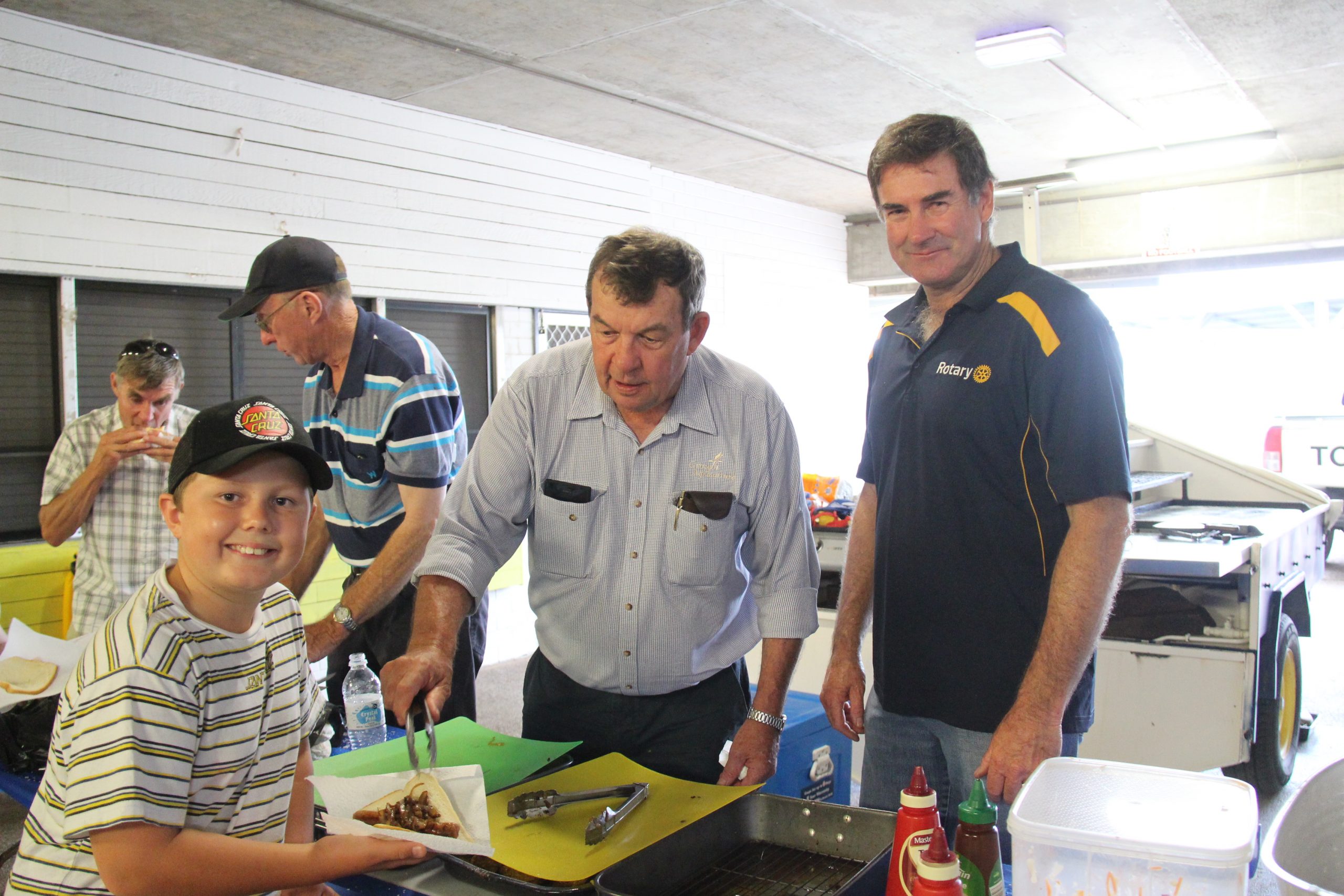 Billy Shearin being served up a sausage sandwich by Rotarians Kerry Watts and David Grellman at the Bush Bots launch last Monday.