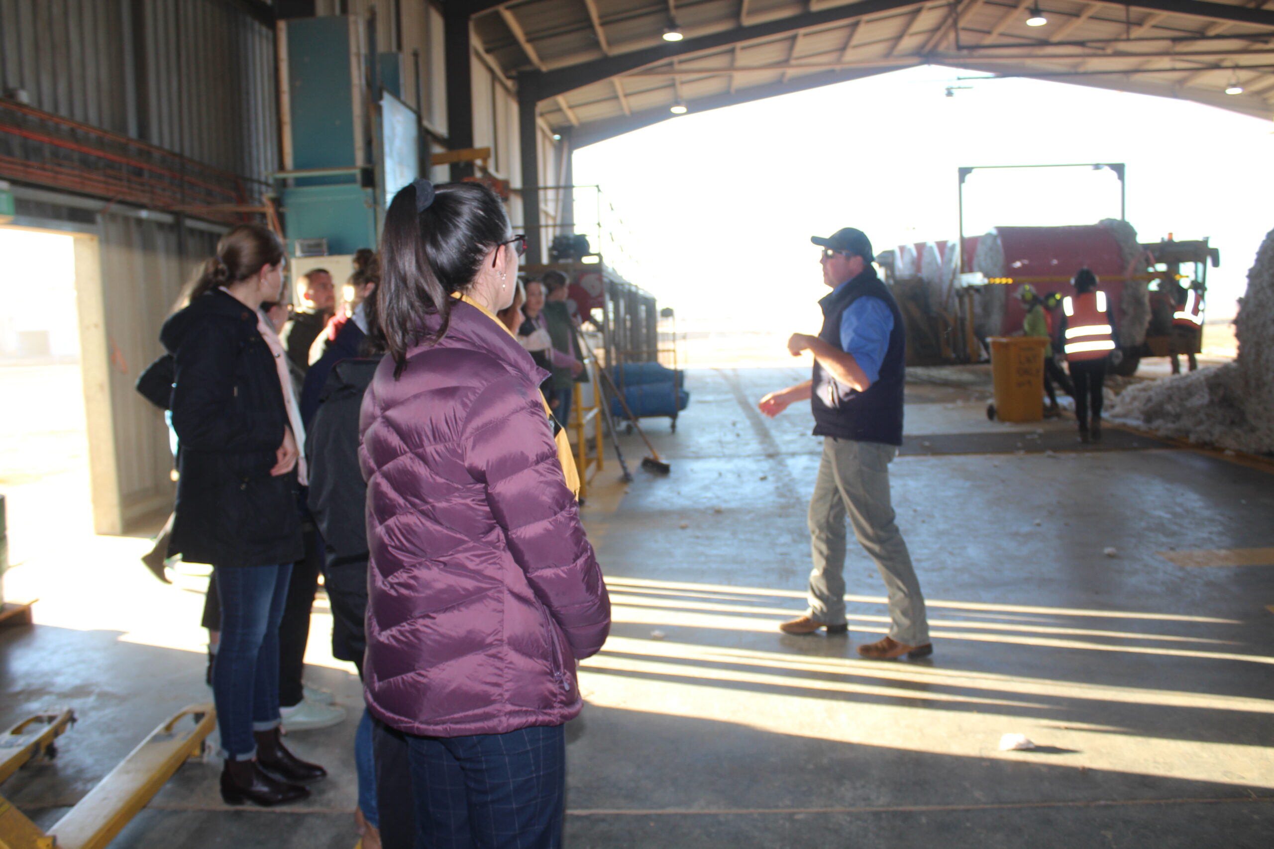 Ben Palmer addressing one of the groups, explaining the cotton bale deseeding process from inside the ginning shed.