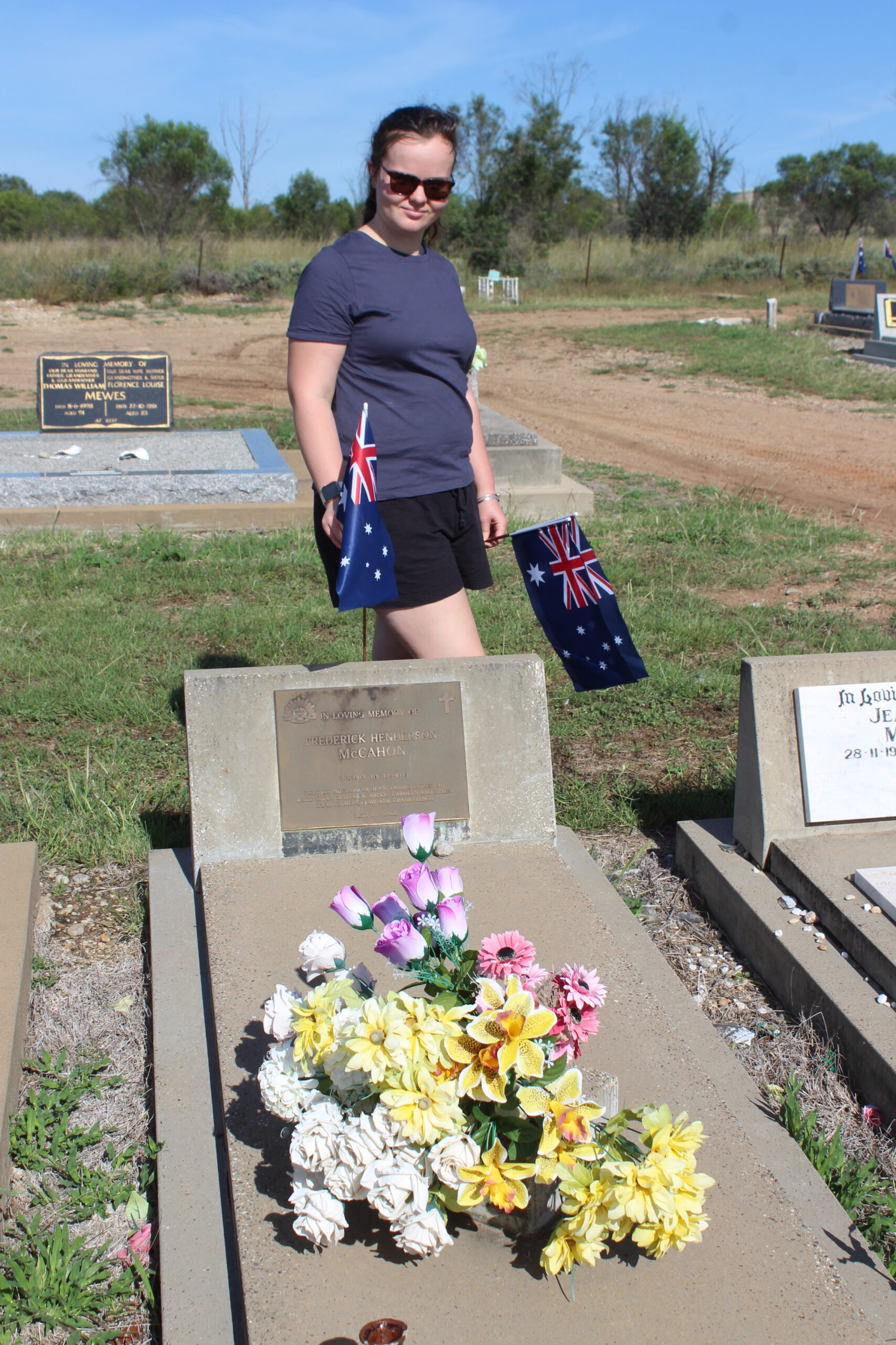 Zara Whelan placing a flag on Fredrick McCahon’s grave.