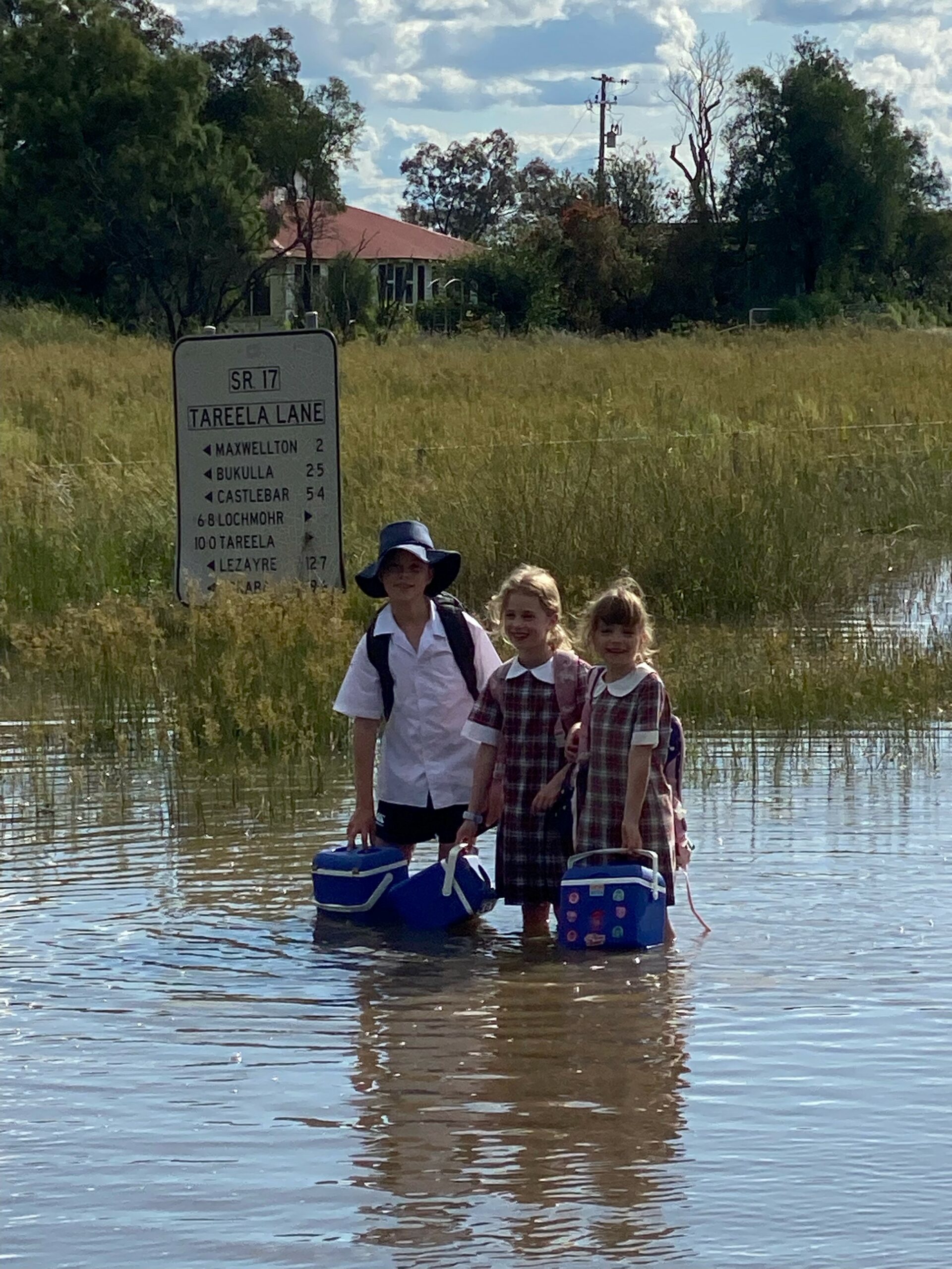 Burren Junction Public School students Maggie, Harry and Rachel Powell on their way to school during the recent floods