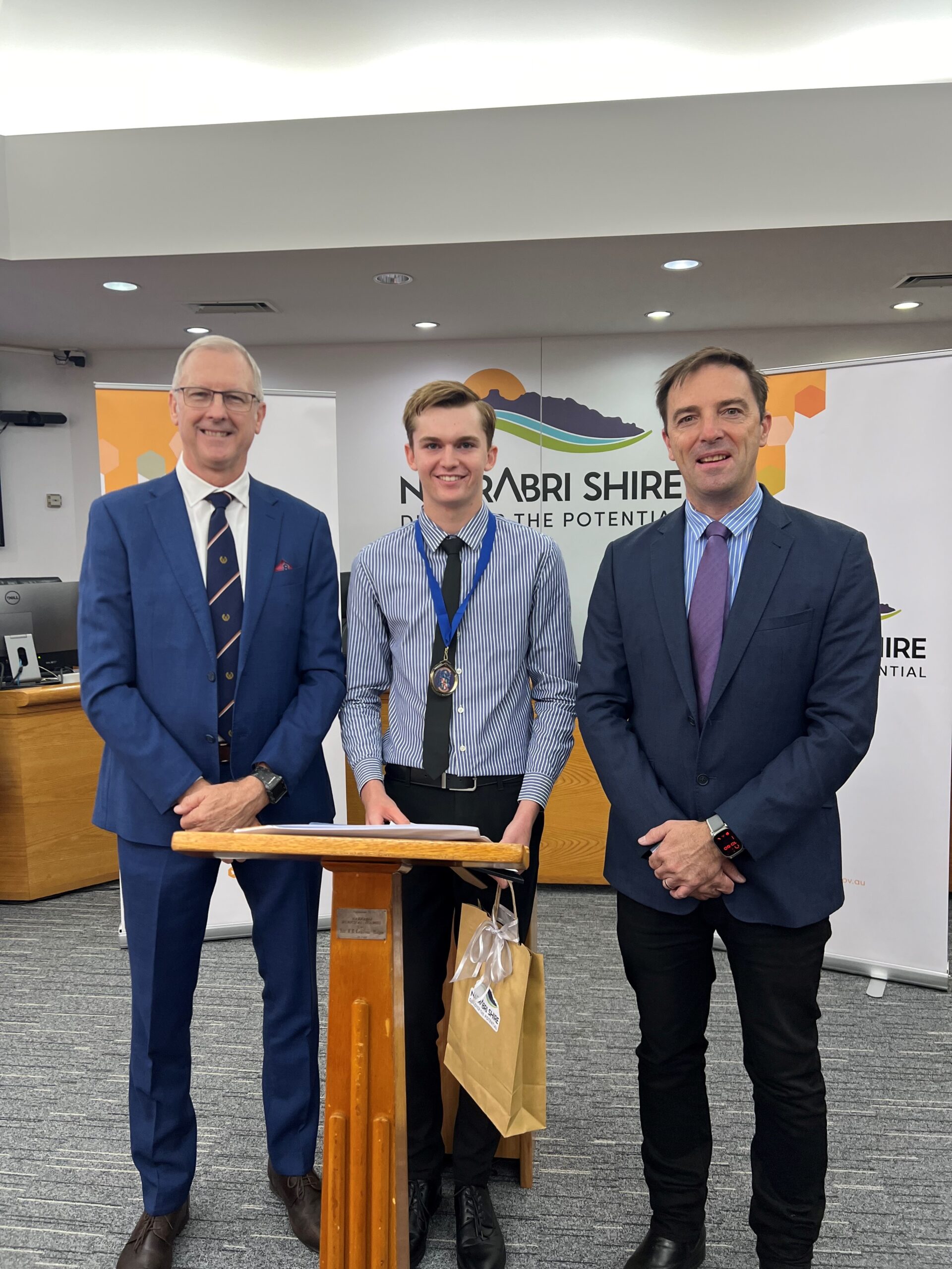 Daniel Smith is congratulated on receiving the 2024 Lillian Hulbert Memorial Prize by David Willets (grandson of Lillian Hulbert), left, and mayor Darrell Tiemens.